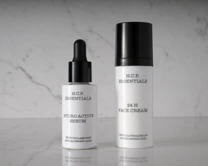 Vegan & fragrance free skincare from N.C.P. Hydration kit with 24 H Face Cream a white bottle with black text and black cap & Hydro Active Serum a white bottle with black text and black pipette. Picture is black and white with a marble background.